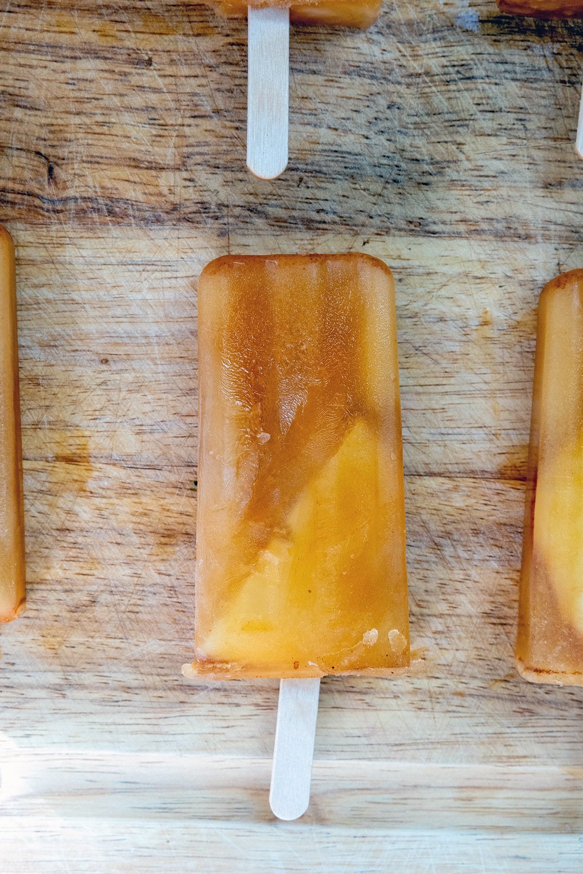 Apple cider popsicles on wood cutting board.