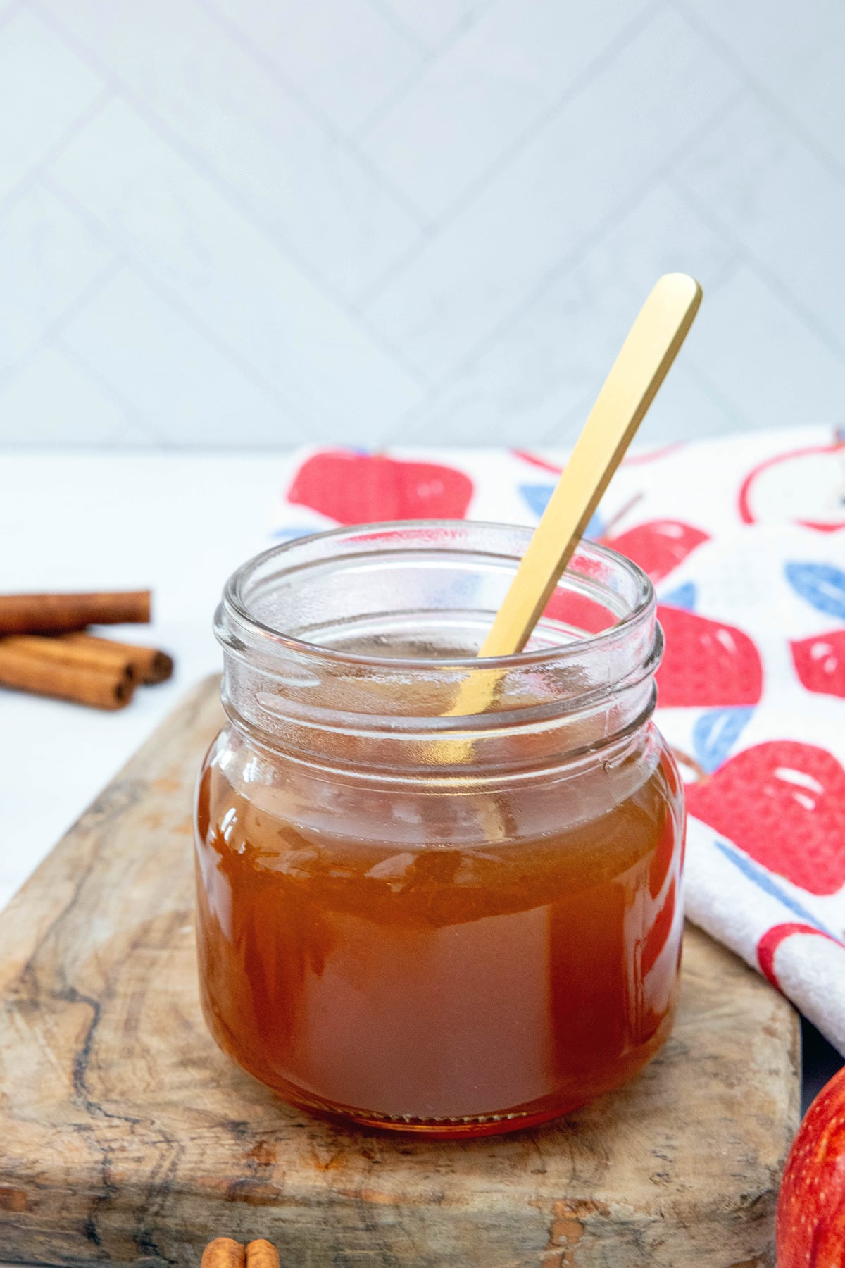 Apple cider syrup in a small mason jar with a spoon.
