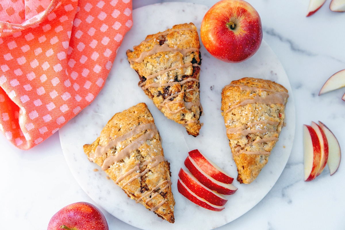 Landscape overhead view of three apple cinnamon scones with apple slices all around.