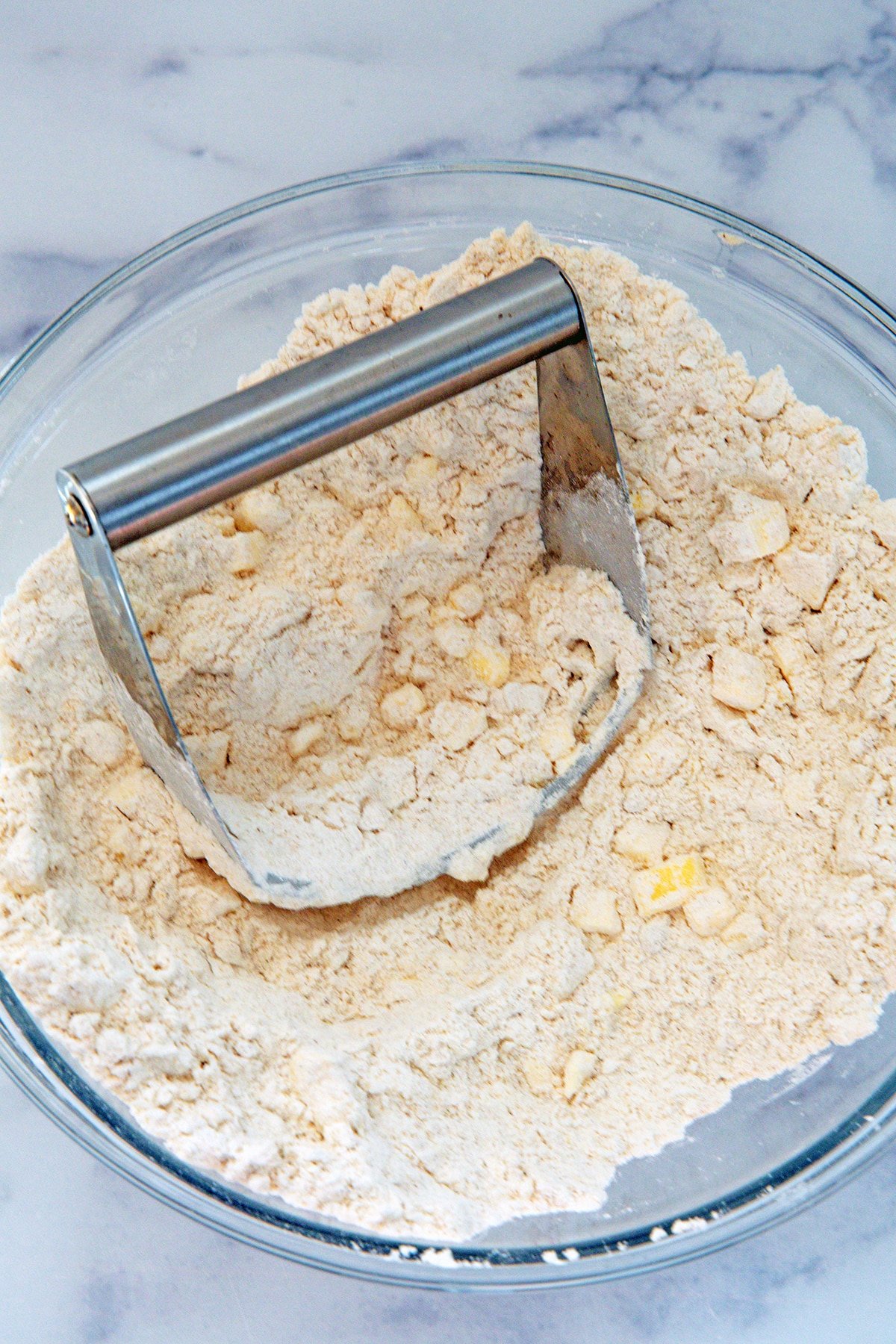 Flour mixture in bowl with pastry cutter blending butter.