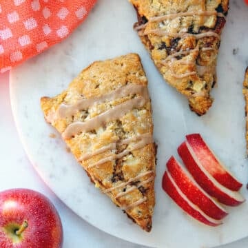 Overhead closeup view of an apple cinnamon scone with icing drizzle and sliced apples.