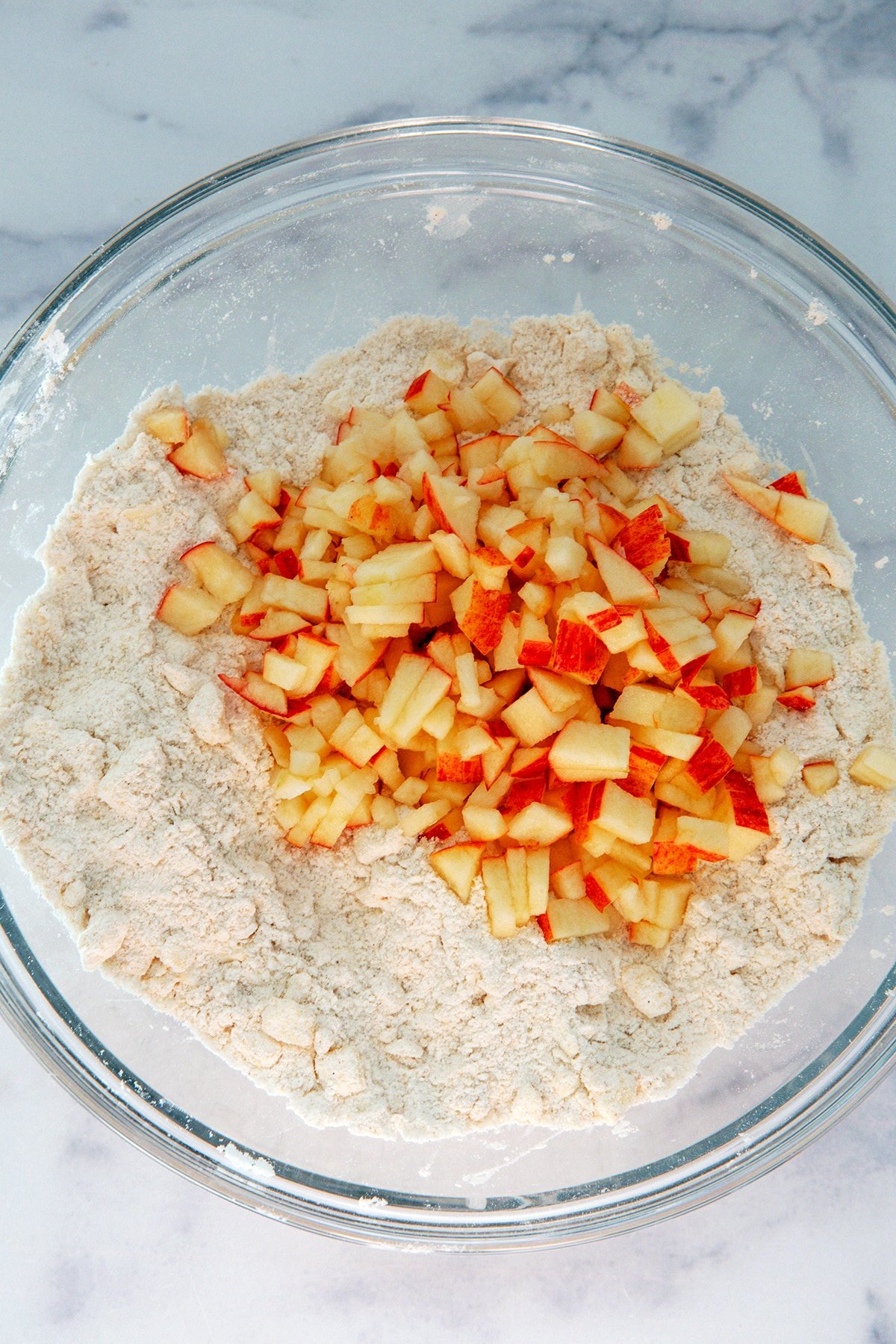 Chopped apple in bowl with flour mixture.