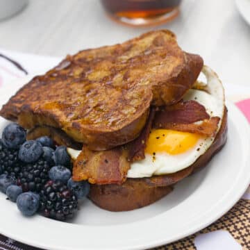 Closeup view of Autumn french toast egg sandwich with bacon and berries on the side.