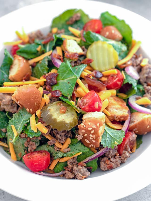 Close-up view of a bacon cheeseburger kale salad in a bowl.