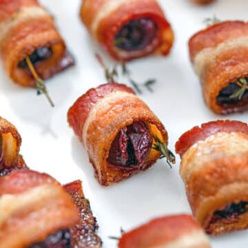 Closeup view of bacon-wrapped cherries with sprigs of thyme.