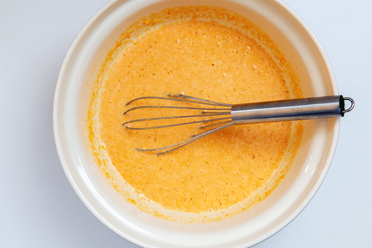 Liquid for baked pumpkin oatmeal in bowl with a whisk.