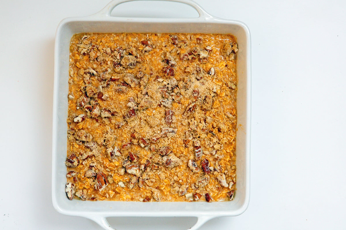 Baked pumpkin oatmeal mixture poured into baking dish and topped with pecan mixture.