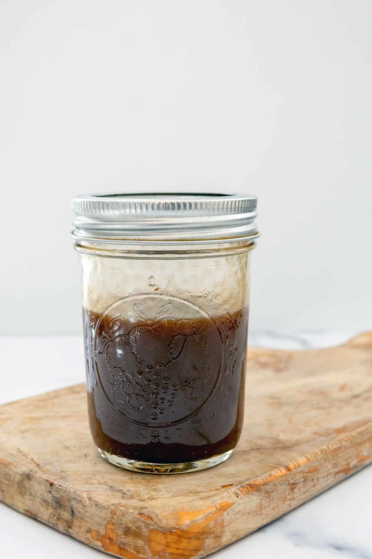 Head-on view of a small jar of balsamic vinaigrette dressing.