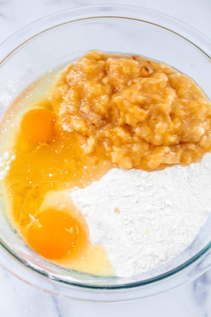 Cake mix in bowl with eggs, oil, and mashed banana.