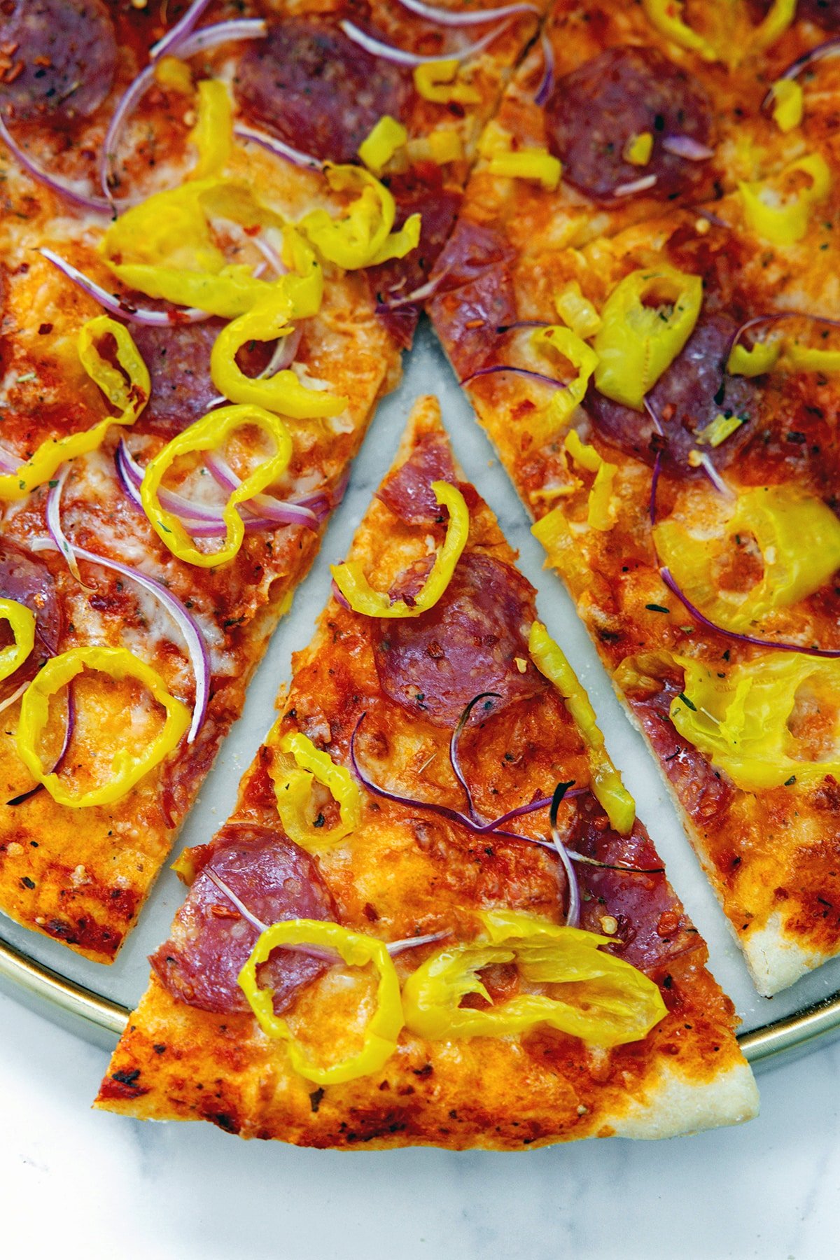 Overhead view of a slice of banana pepper pizza pulled out from the rest of the pizza.