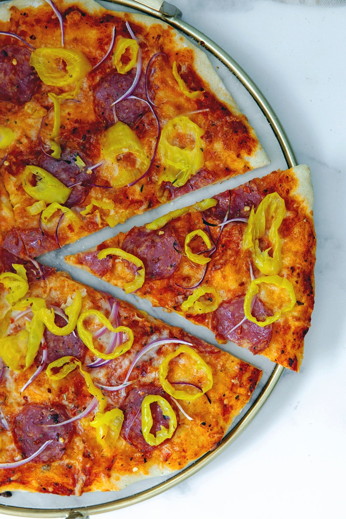 Overhead view of banana pepper pizza with slice pulled out of the right side.