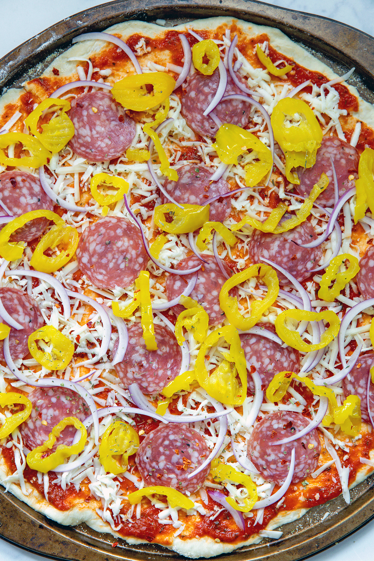 Closeup of a banana pepper pizza assembled but not baked.