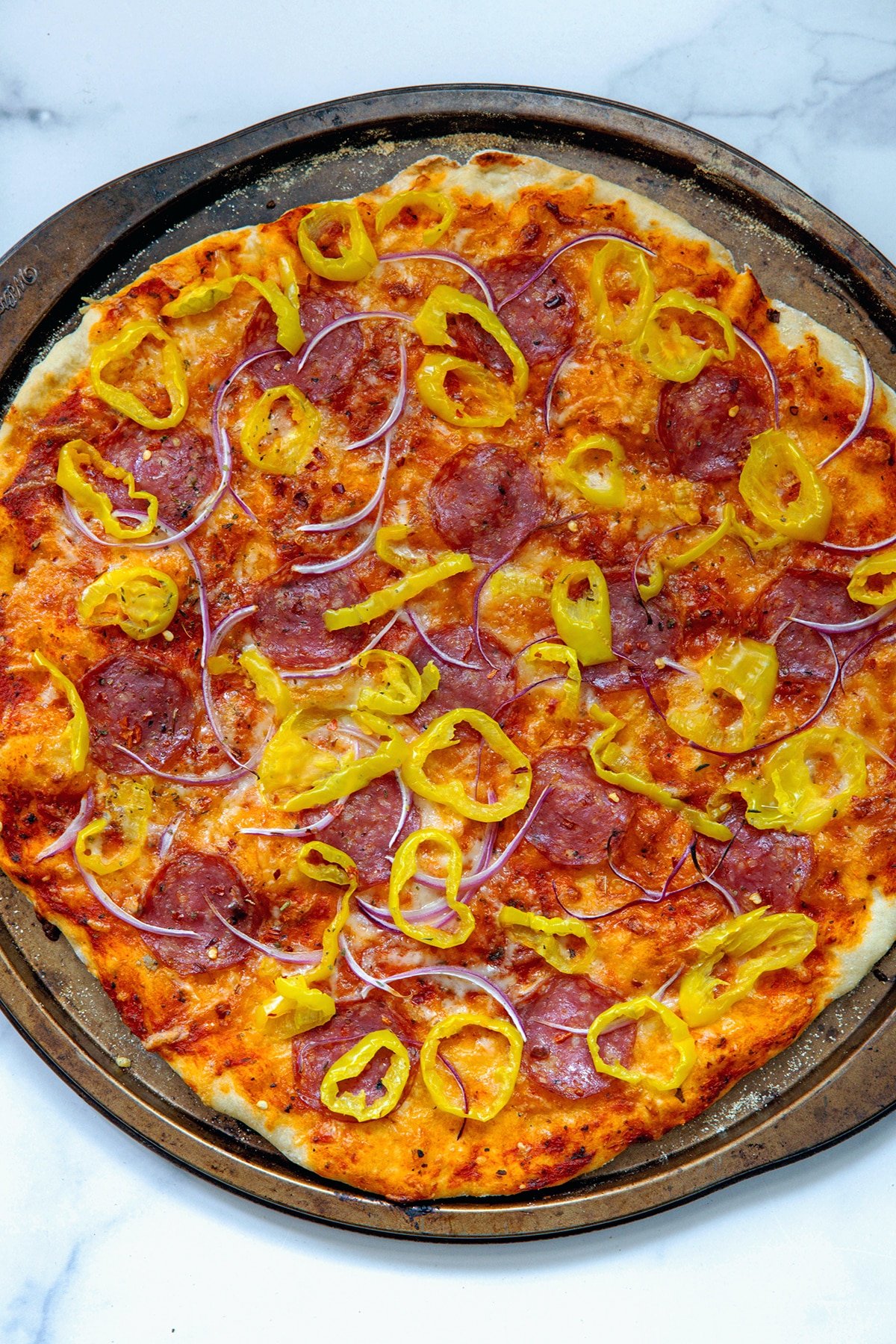 Banana pepper pizza on pan just out of the oven.