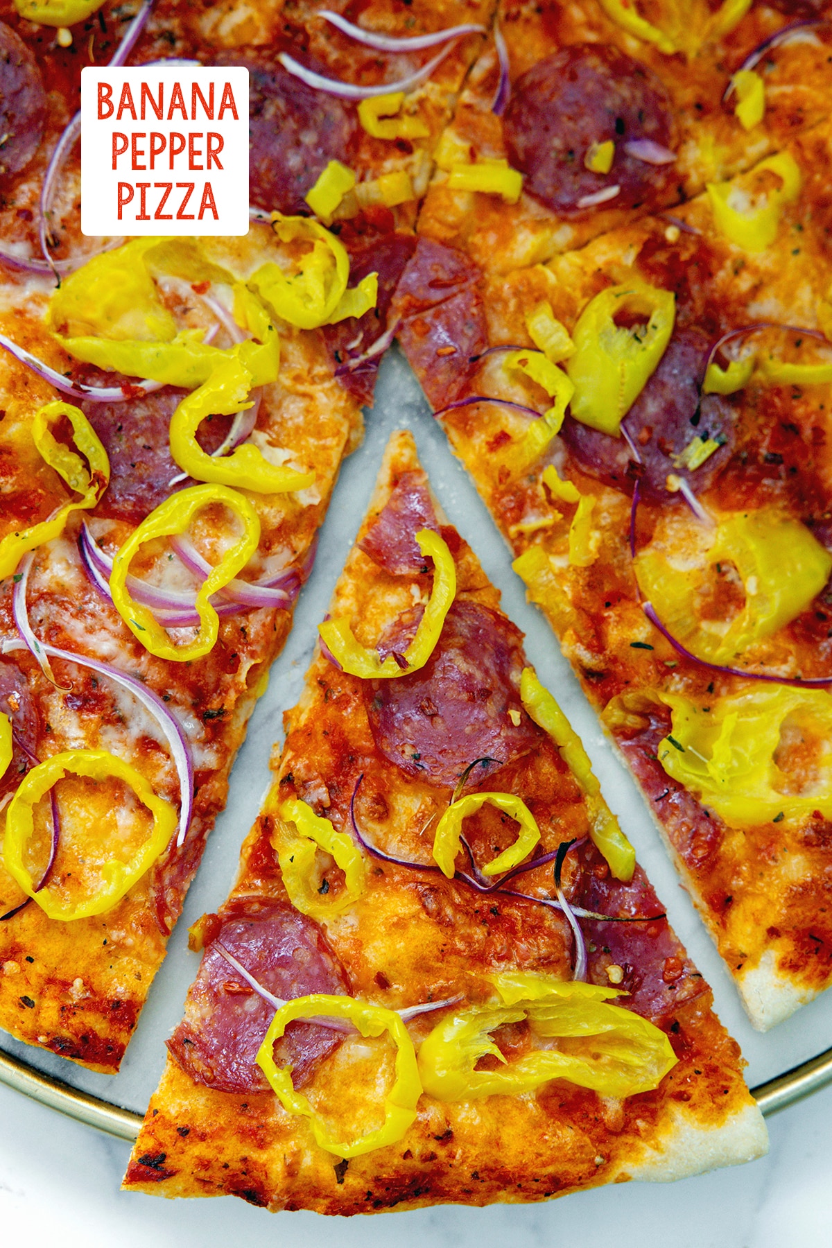 Overhead view of a slice of banana pepper pizza pulled out from the rest of the pizza with recipe title at top.