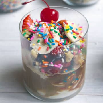 Closeup view of a banana split affogato with sprinkles and a cherry on top.