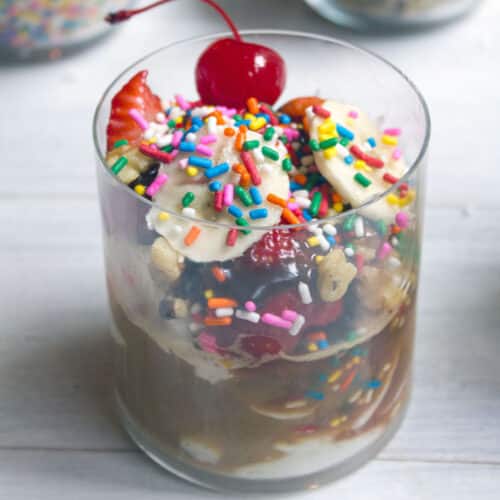 Closeup view of a banana split affogato with sprinkles and a cherry on top.