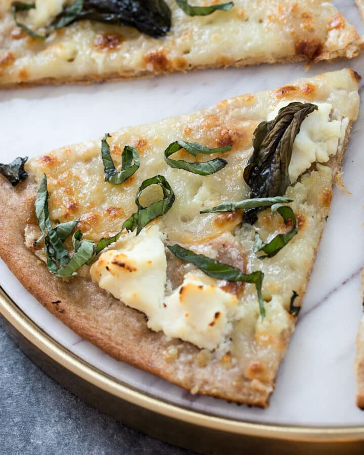 Closeup of a basil and garlic olive oil pizza slice.