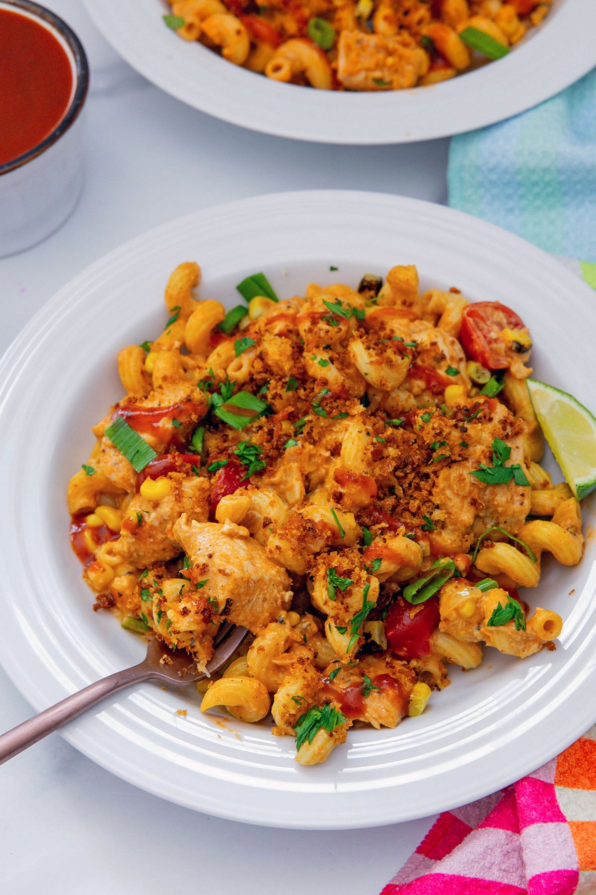 Overhead view of a dish of BBQ chicken pasta with panko topping with fork in it.