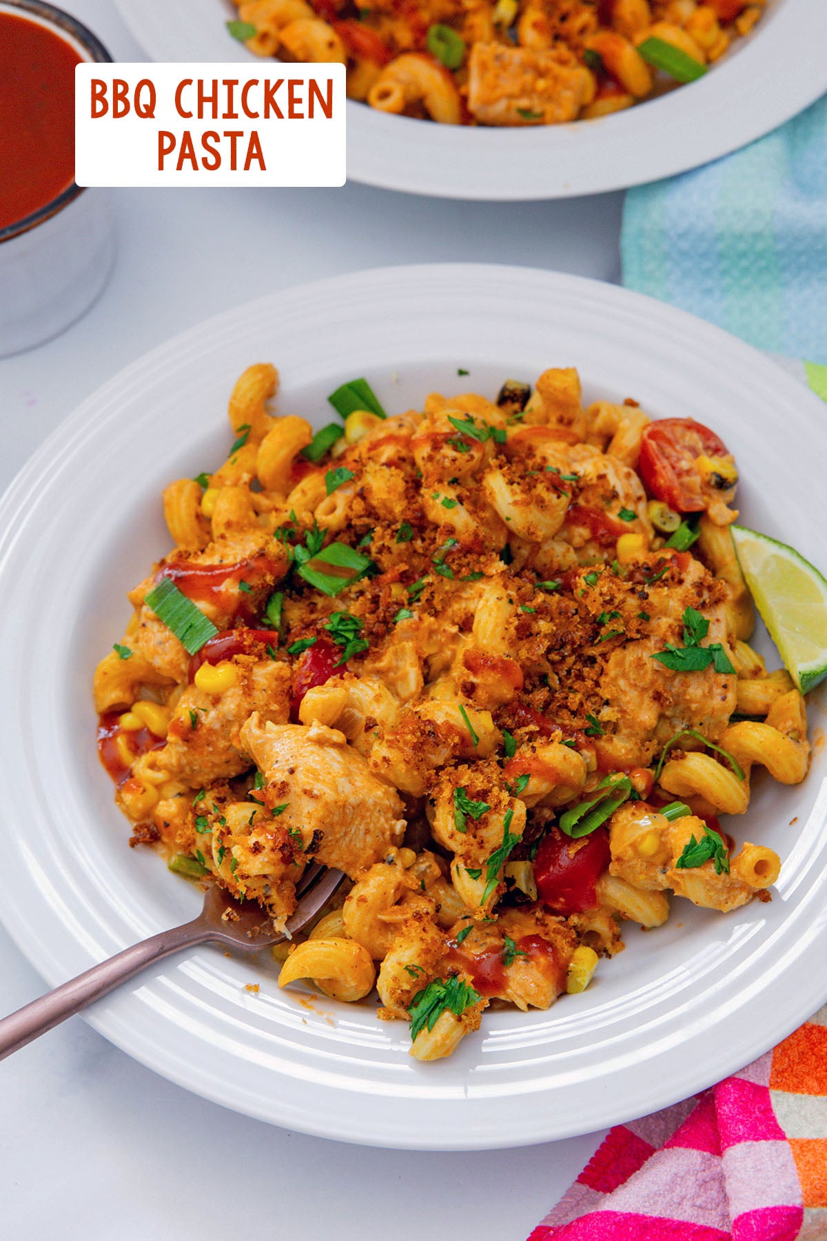 Overhead view of a dish of BBQ chicken pasta with panko topping with fork in it and recipe title at top.