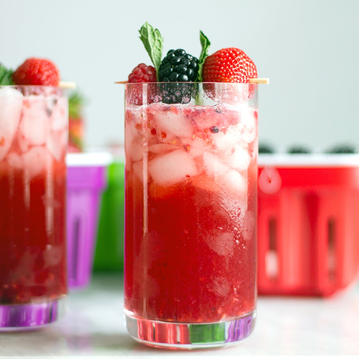 Head-on view of a berry gin cocktail with strawberry, blackberry, and raspberry garnish.