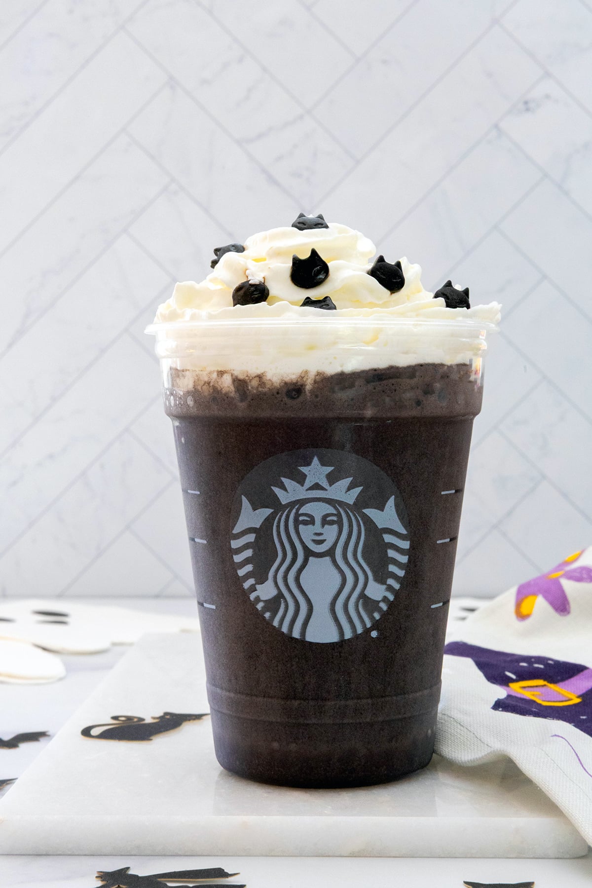 Head-on view of a Black Cat Frappuccino with whipped cream and cat sprinkles.