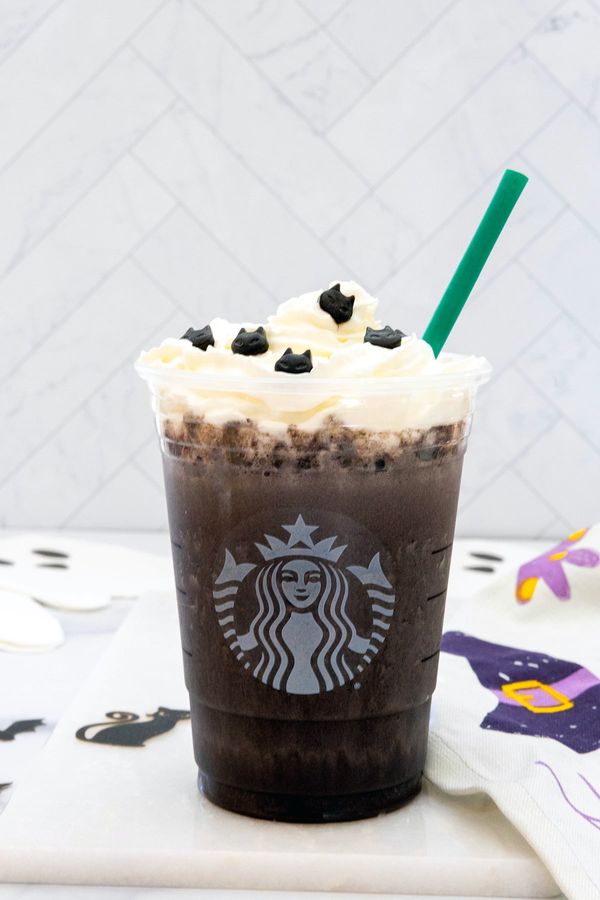 Head-on close up view of Black Cat Frappuccino in Starbucks cup with green straw.