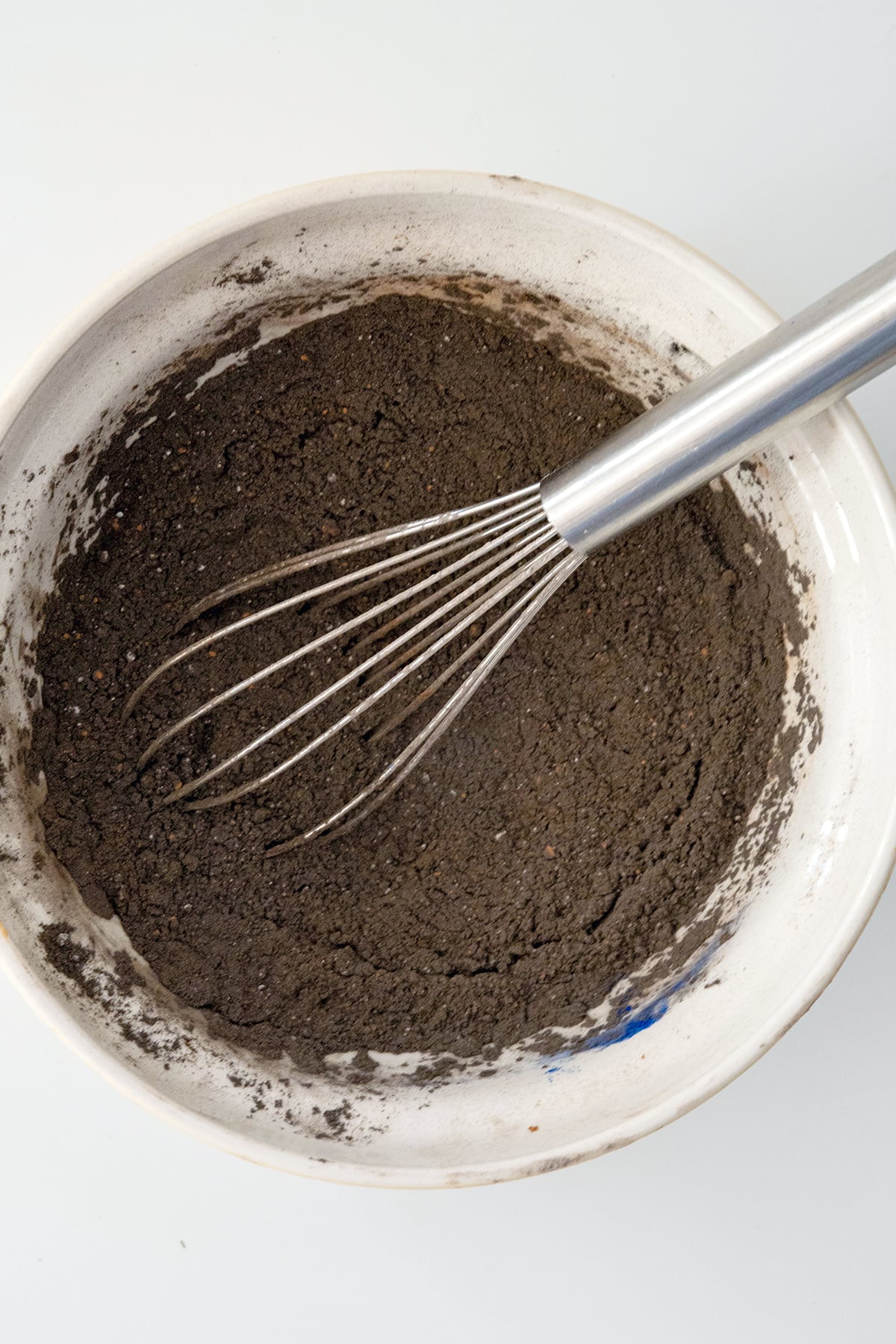 Chocolate cake powder in bowl with whisk.