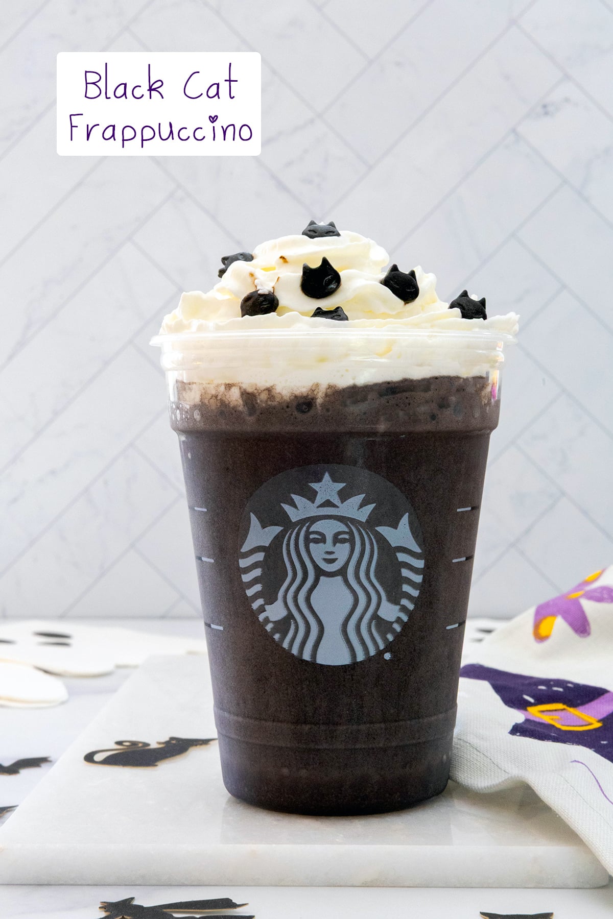 Head-on view of a Black Cat Frappuccino with whipped cream and cat sprinkles with recipe title at top.