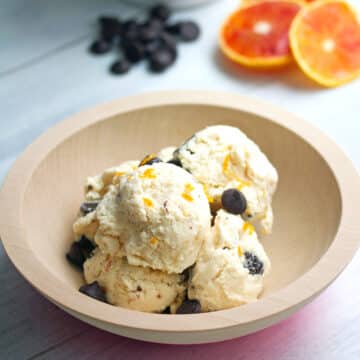 Closeup view of a bowl of blood orange ice cream with dark chocolate chips.