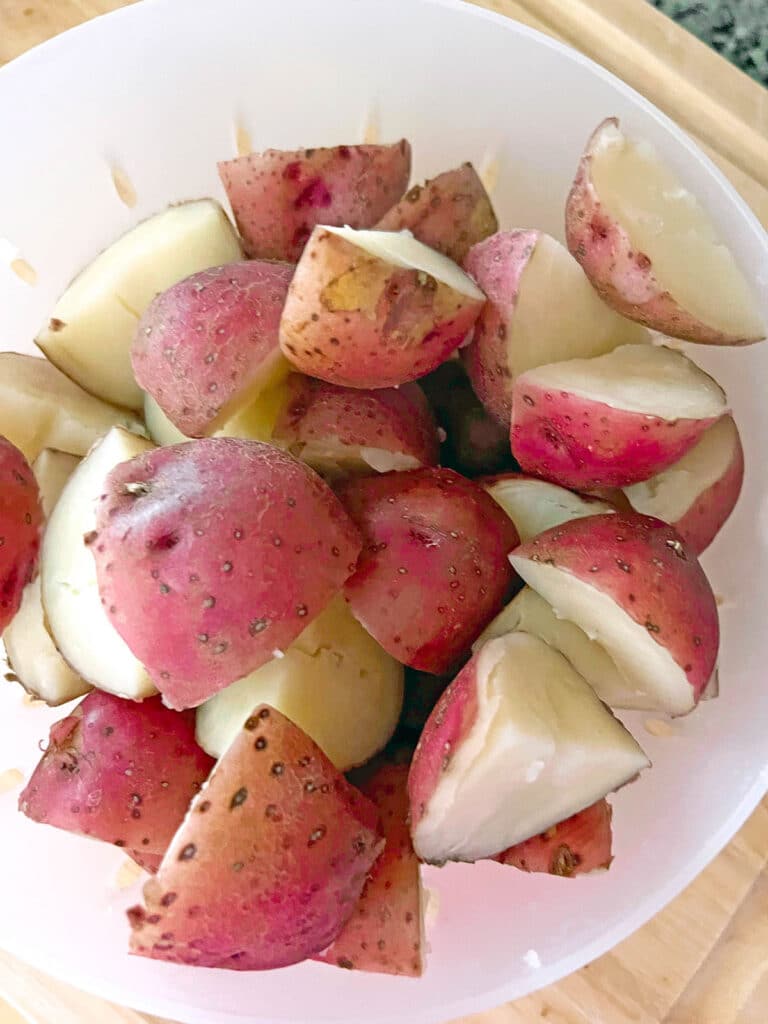 Boiled quartered red potatoes in a strainer.