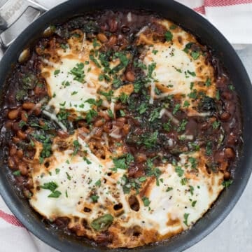 Overhead closeup view of a skillet with Boston baked beans and eggs.