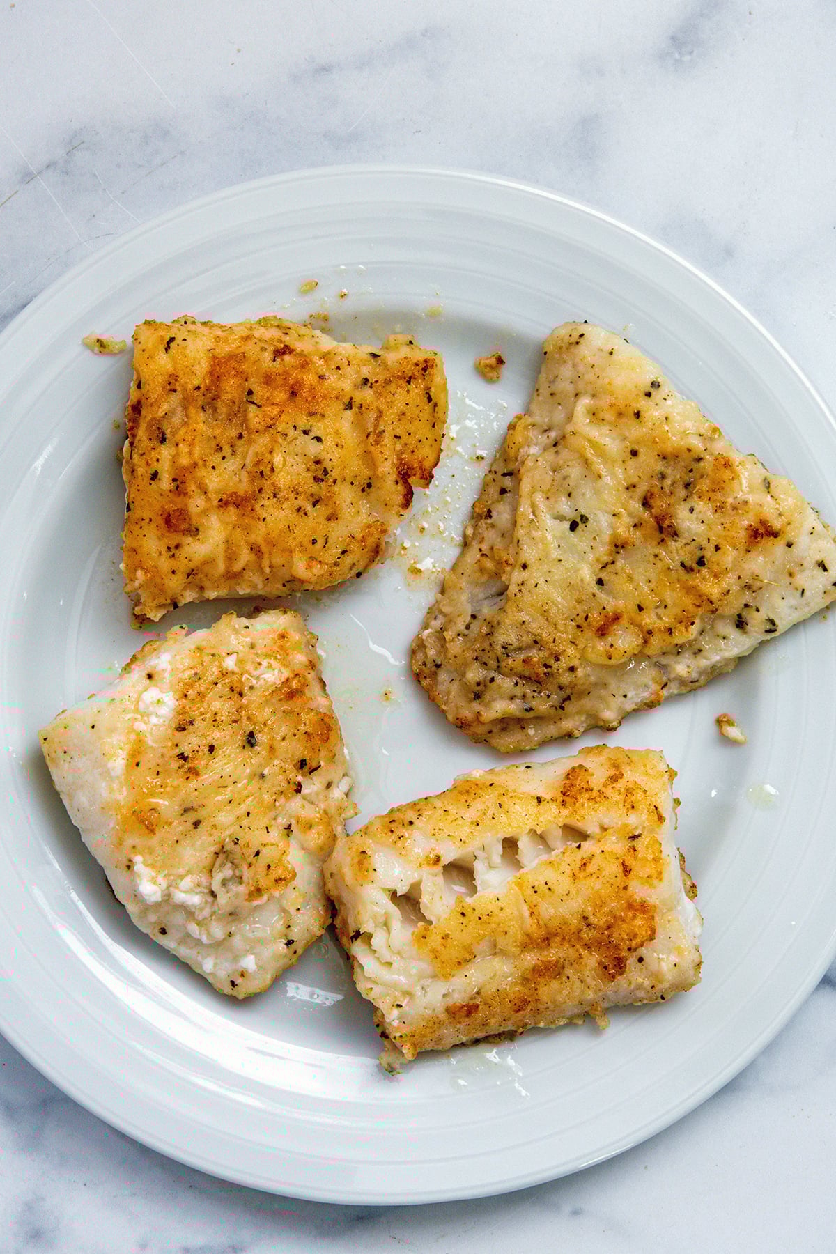 Golden cod filets on a white plate.