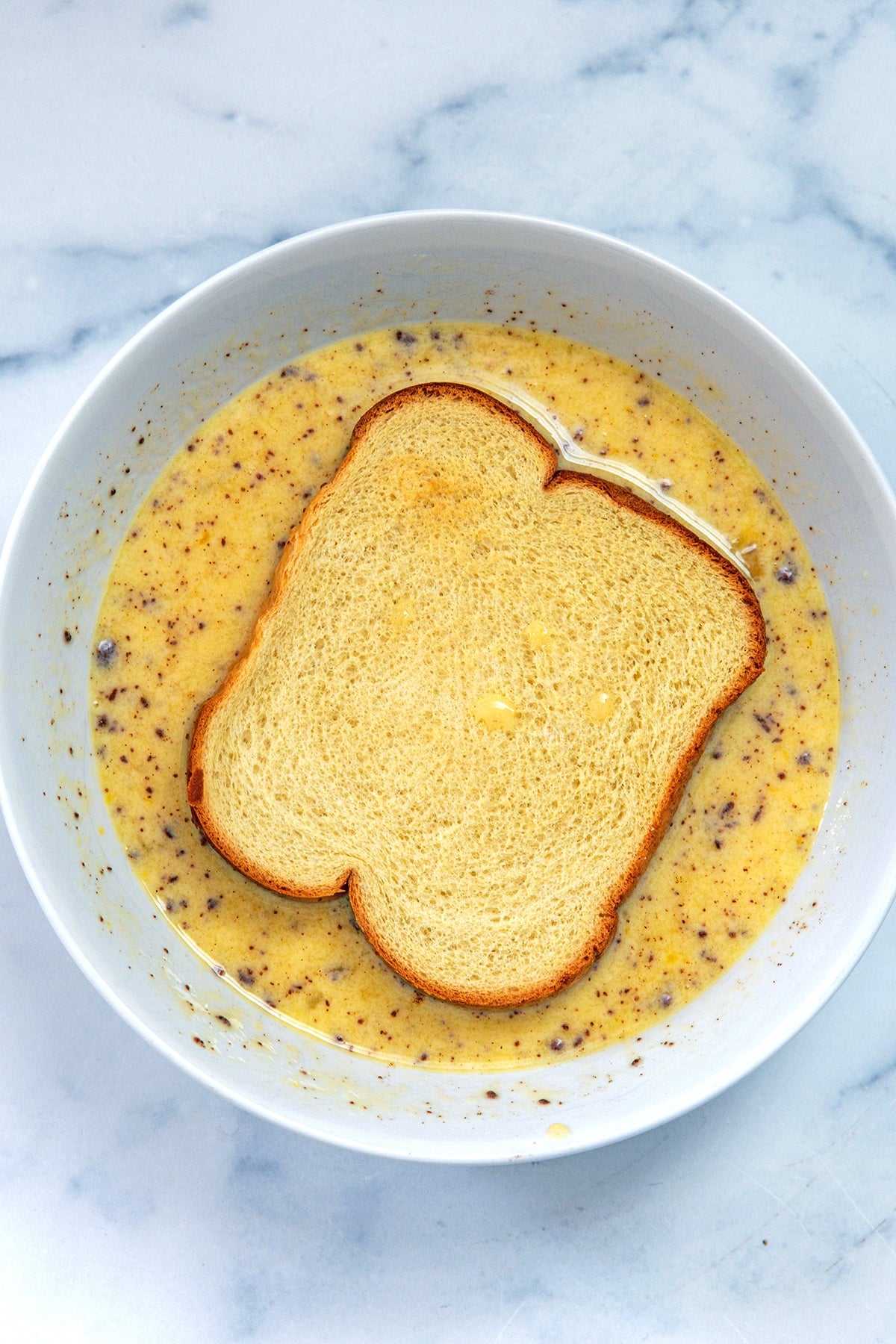 Slice of brioche dunked in an egg and buttermilk mixture.