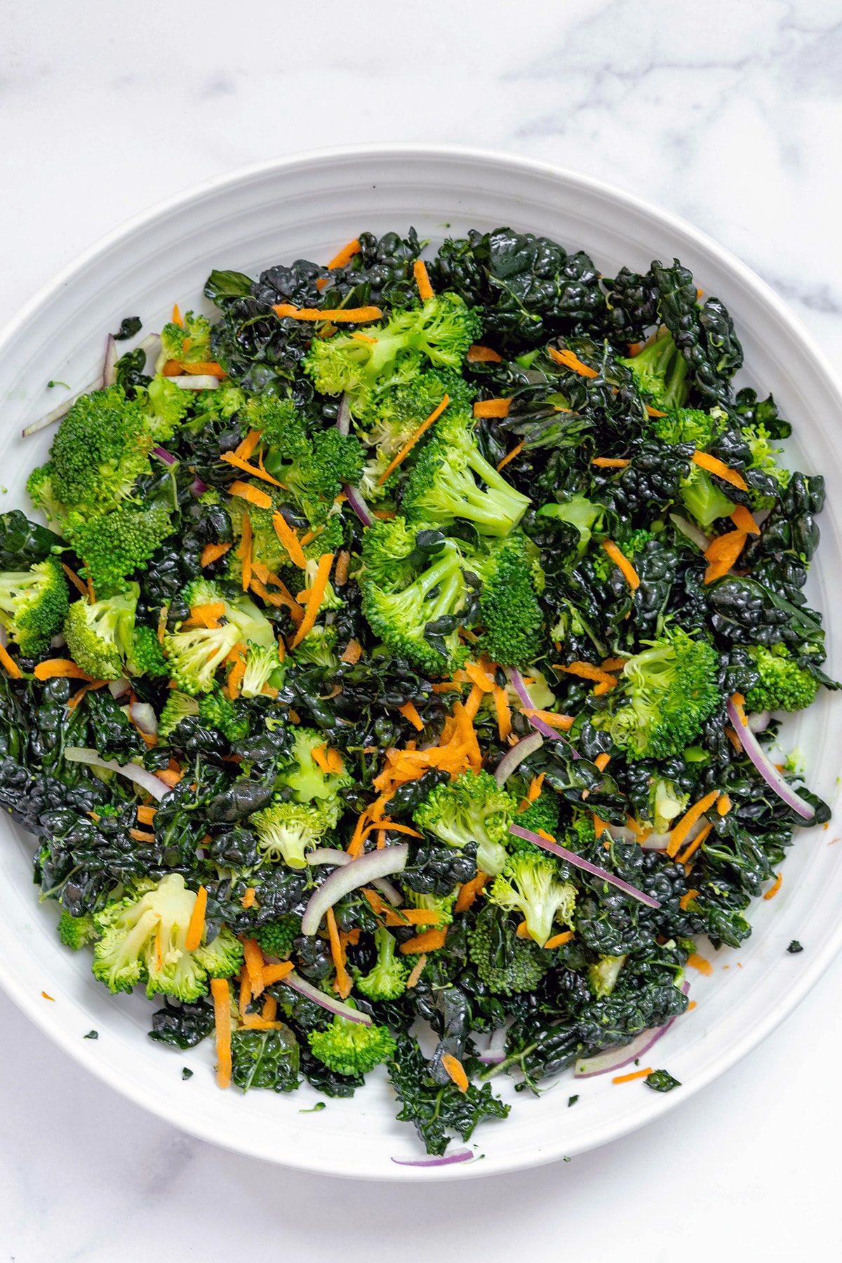 Overhead view of finished broccoli kale salad in white serving bowl.