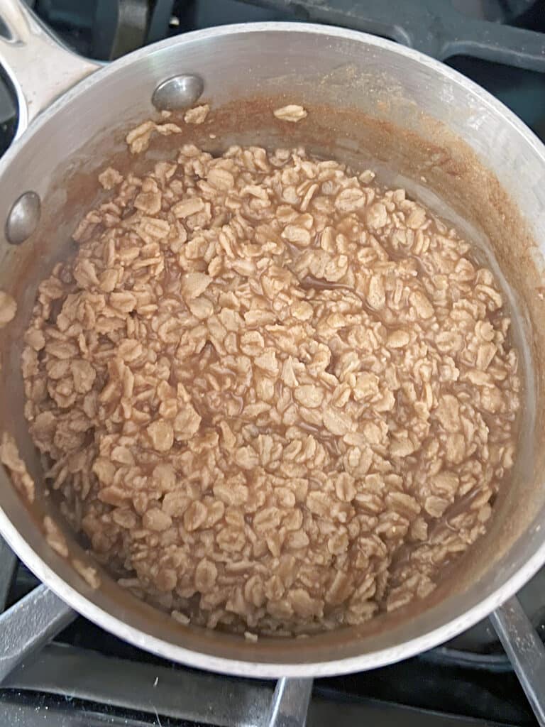 Brown sugar stirred into cinnamon oatmeal in saucepan.