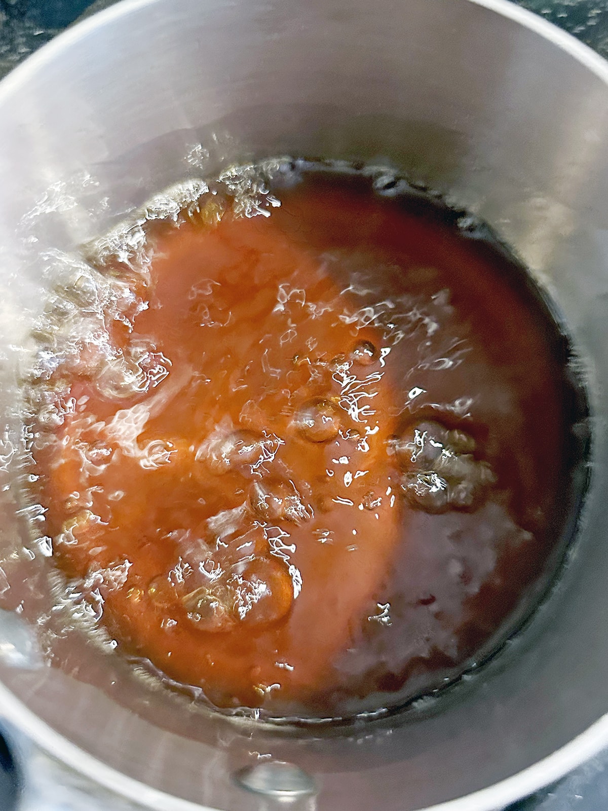Brown sugar syrup boiling in saucepan.