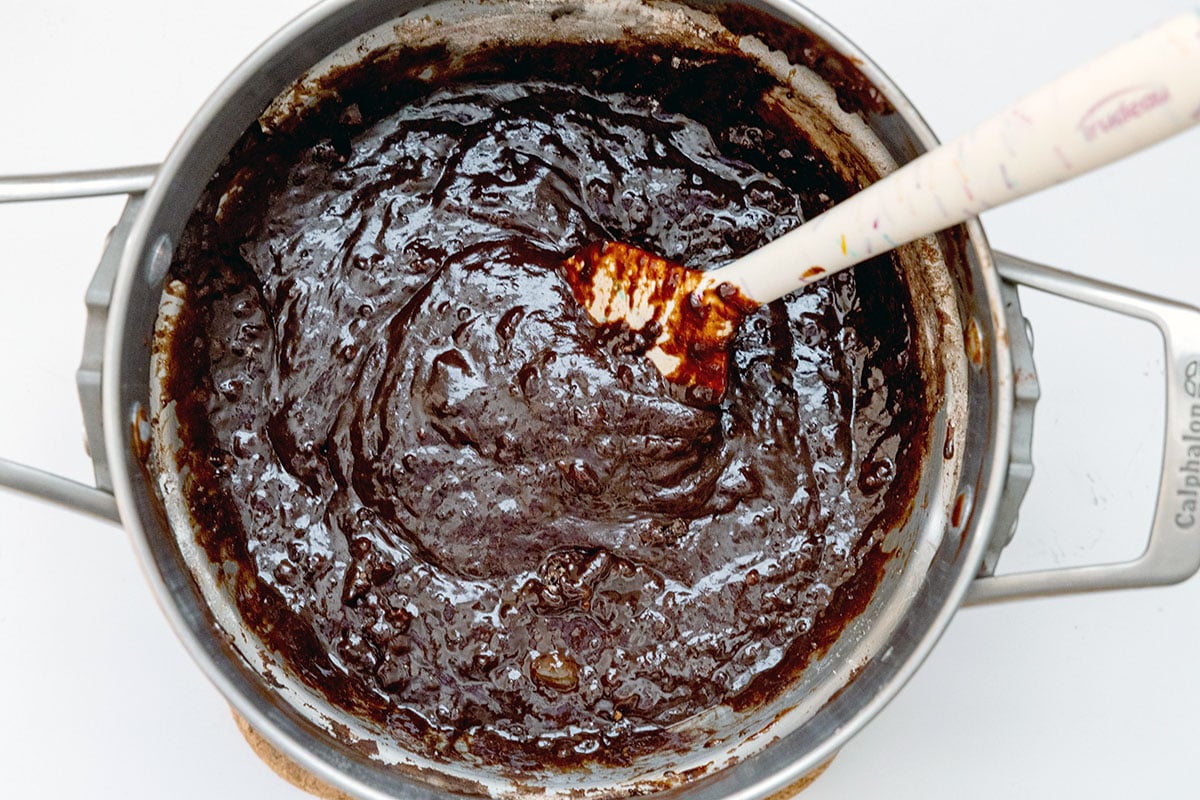 Brownie batter in double boiler with spatula.
