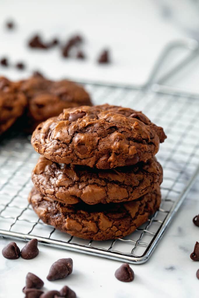 A stack of brownie mix cookies on a metal rack with chocolate chips all around.