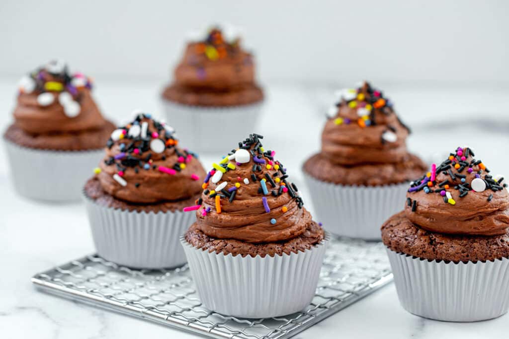 Landscape view of several brownie mix cupcakes with chocolate frosting an sprinkles.