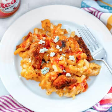 Closeup view of buffalo chicken mac and cheese on a white plate with fork.