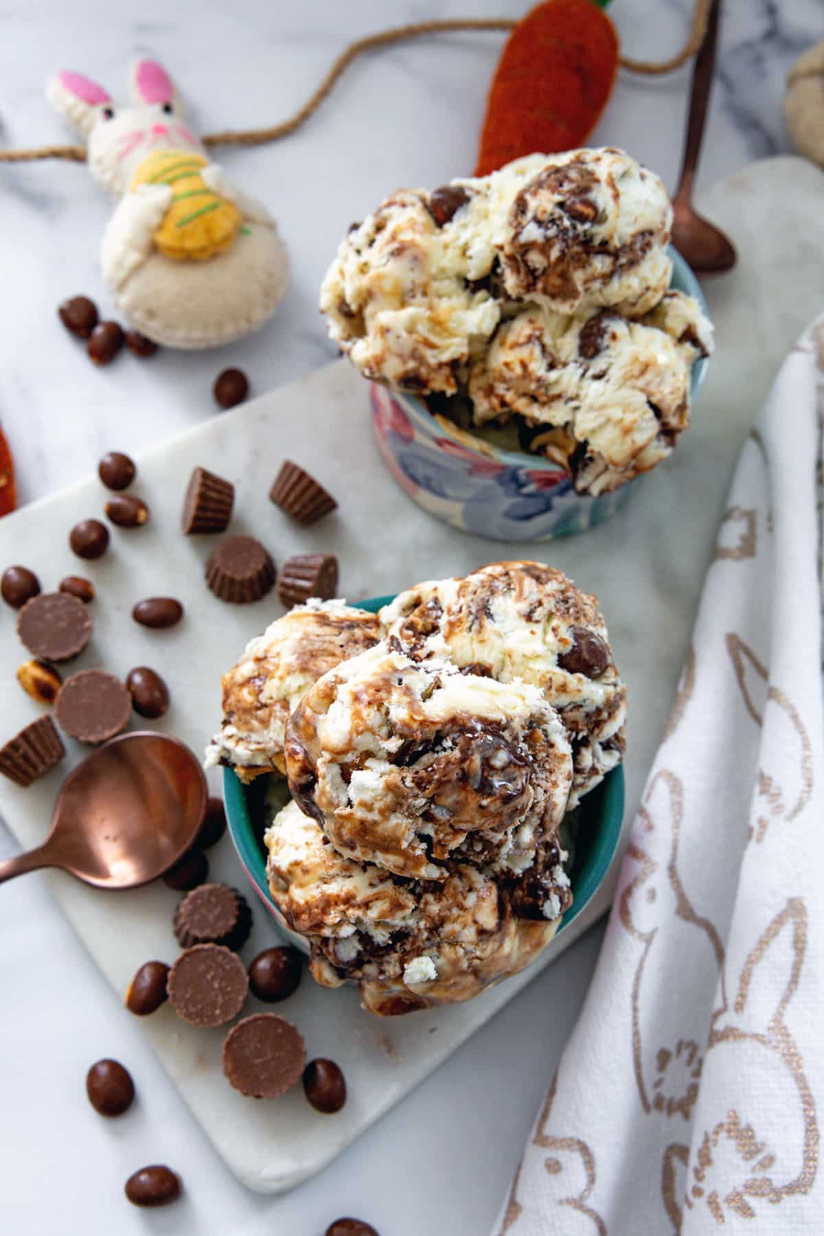 Bird's eye view of two bowls of bunny tracks ice cream with chocolate candies, bunny, and rose gold spoon.