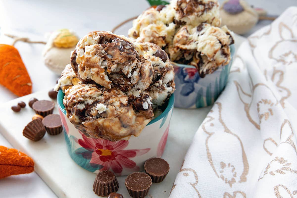 Landscape overhead view of two bowls of bunny tracks ice cream with chocolate candies all around.