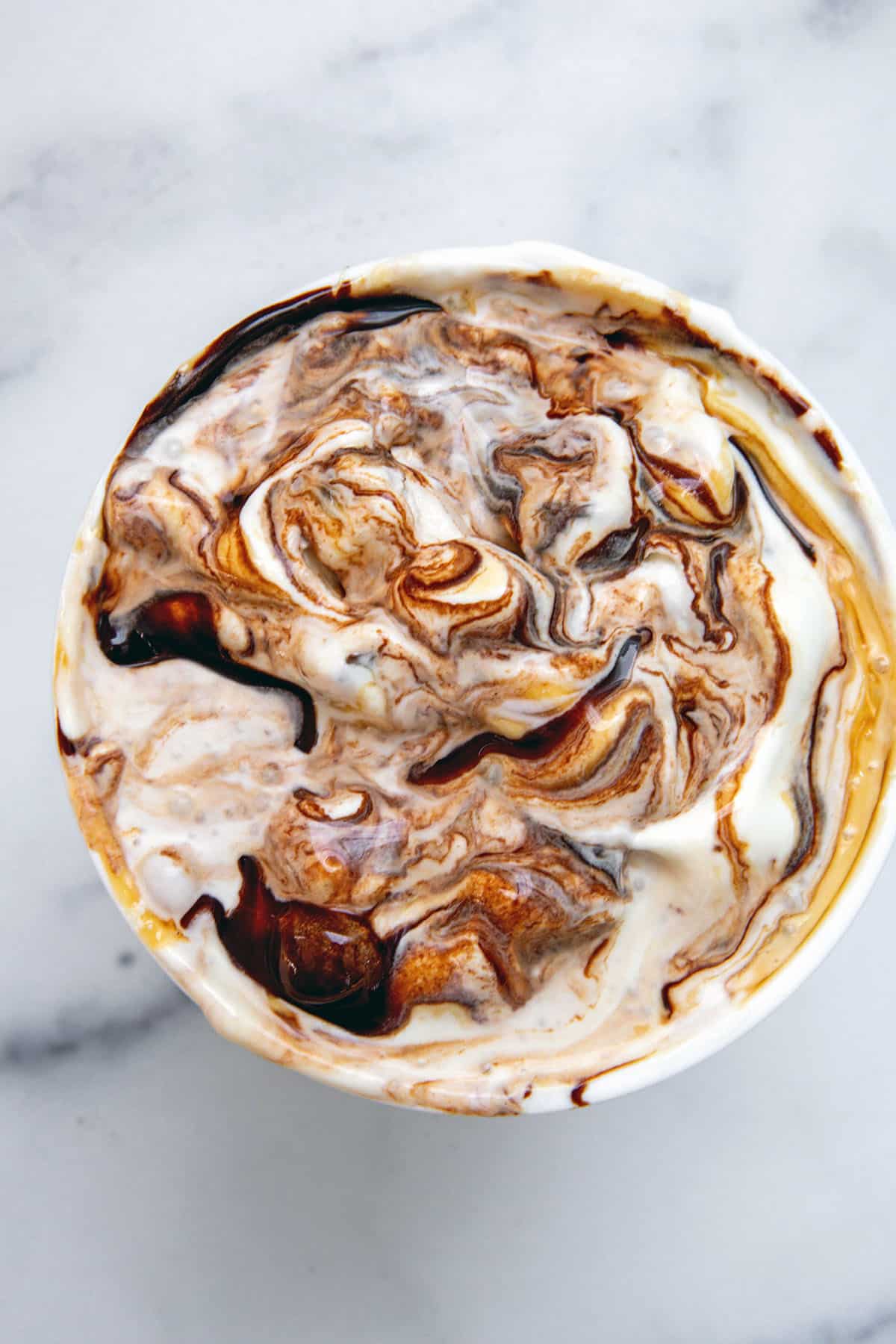 Overhead view of chocolate and caramel sauce swirled ice cream in quart-size container.