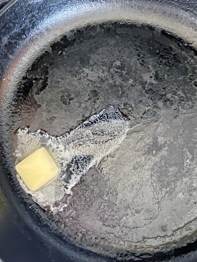 Butter melting in cast iron skillet.