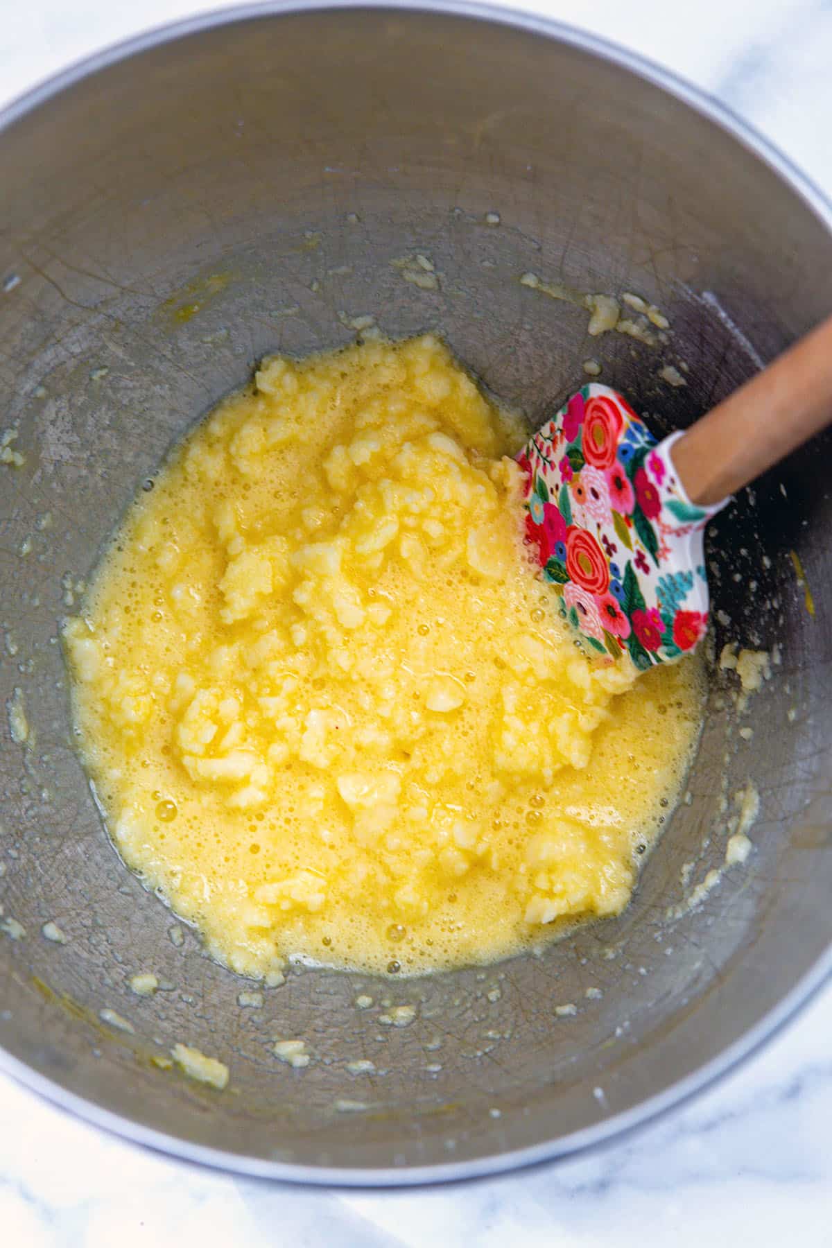 Butter, sugar, and eggs mixed together in mixing bowl.