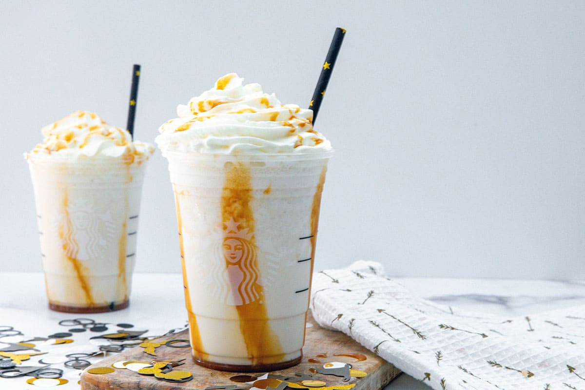 Landscape head-on view of two Butterbeer Frappuccinos with straws.