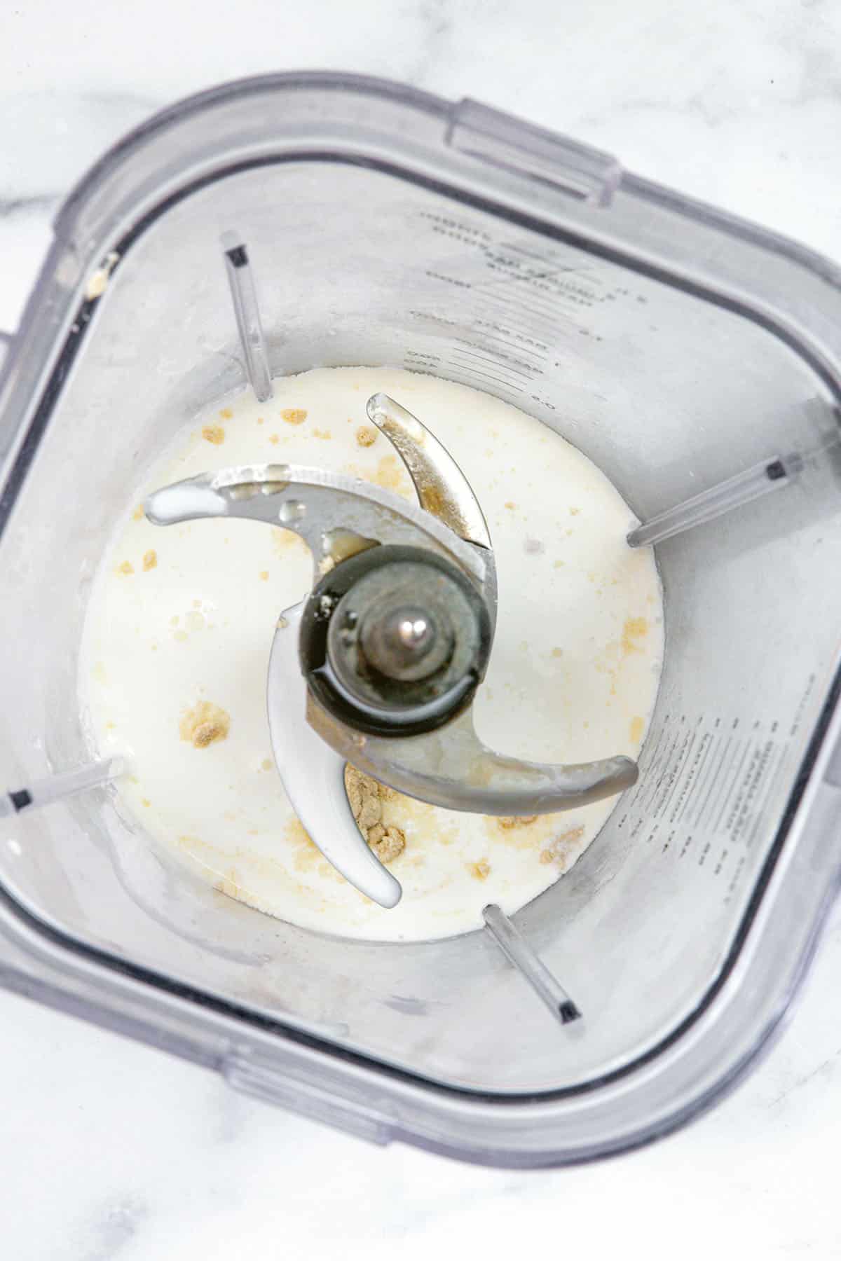 Overhead view of milk and syrups in blender.