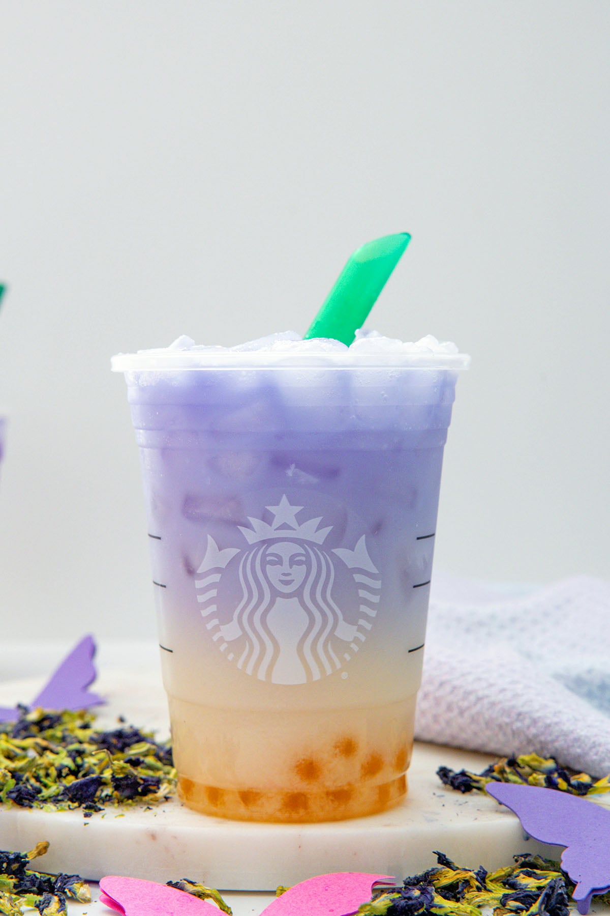 Head-on view of purple and orange ombre Butterfly Drink in Starbucks cup with green straw.