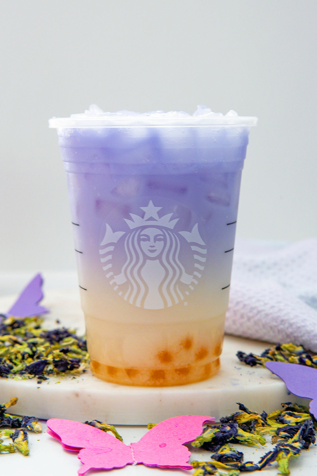Head-on view of a Butterfly Drink in a Starbucks cup with butterfly pea flowers all around.