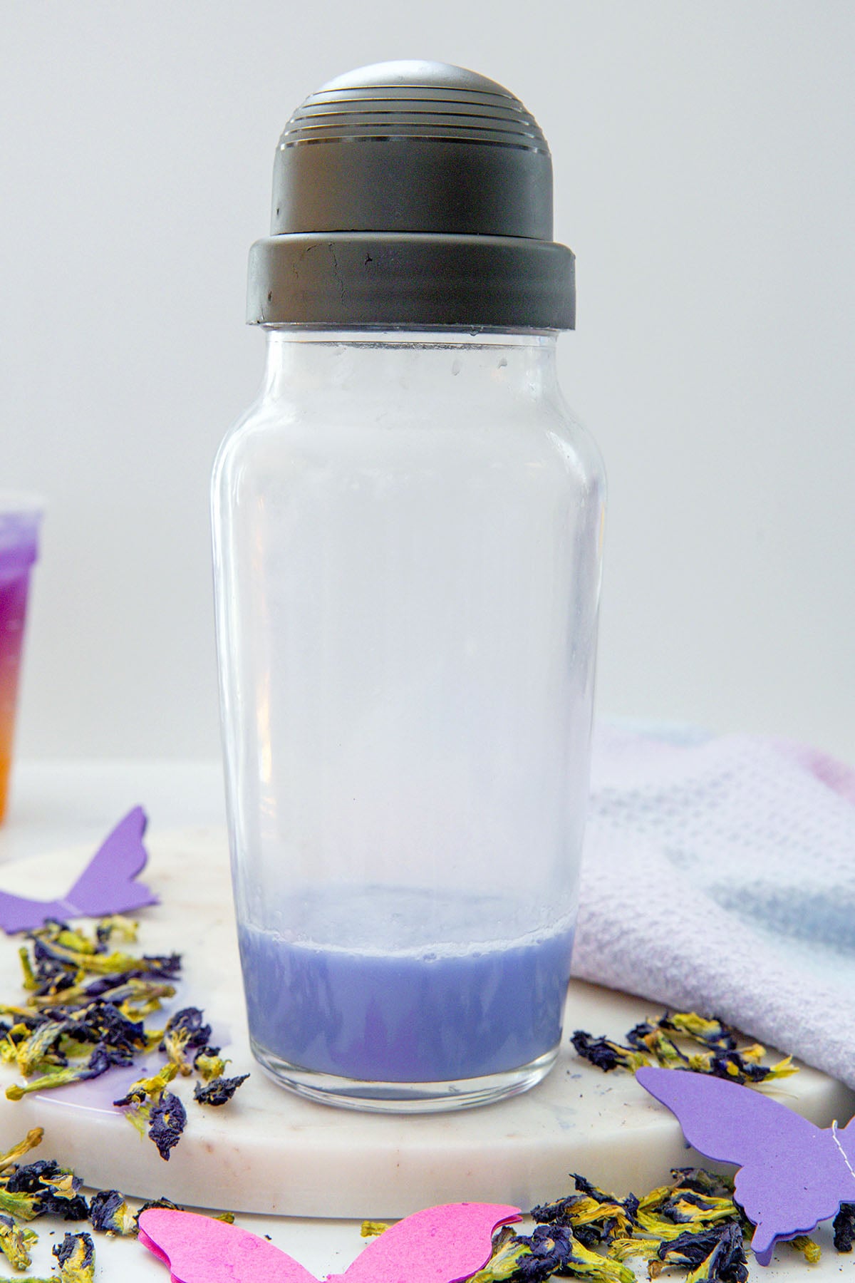 Clear shaker with butterfly pea flower mixture and coconut milk.